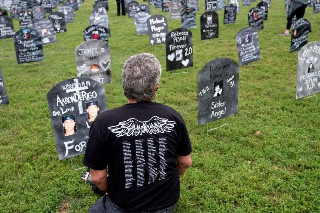 A person who lost a relative to a drug overdose sits among imitation graves set up near the Capitol on Sept. 24. Analysts say Medicare has failed to cover some of the most effective treatments for substance use disorder. 