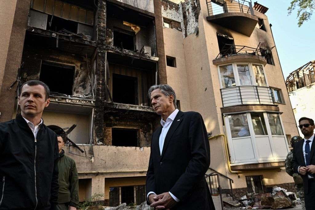 Secretary of State Antony Blinken, center, stands near a damaged residential building during his visit to Irpin on Sept. 8, 2022.