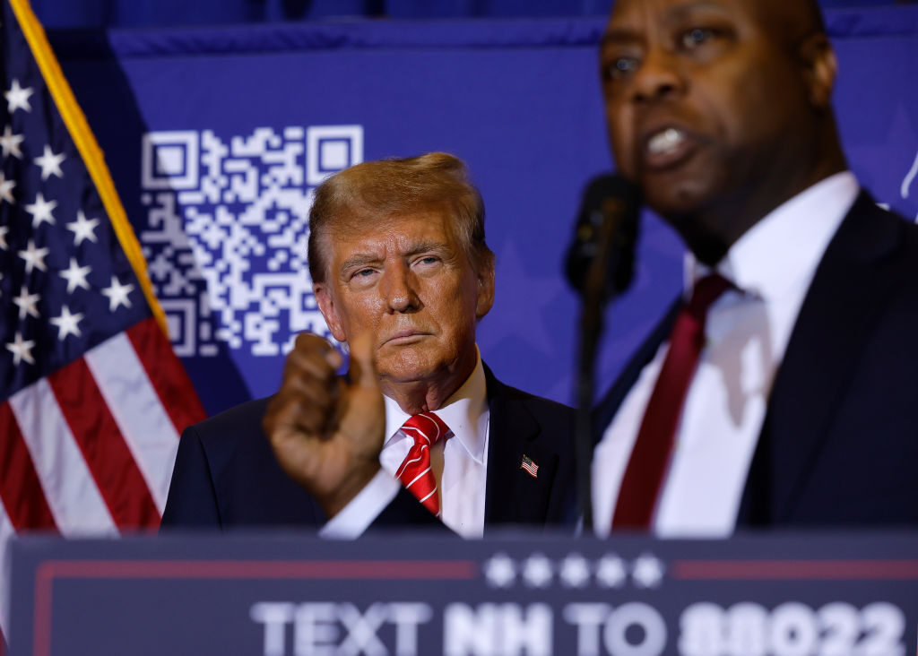 Republican presidential candidate and former President Donald Trump looks on as Sen. Tim Scott, R-S.C., speaks during a campaign rally Friday in Concord, N.H. 