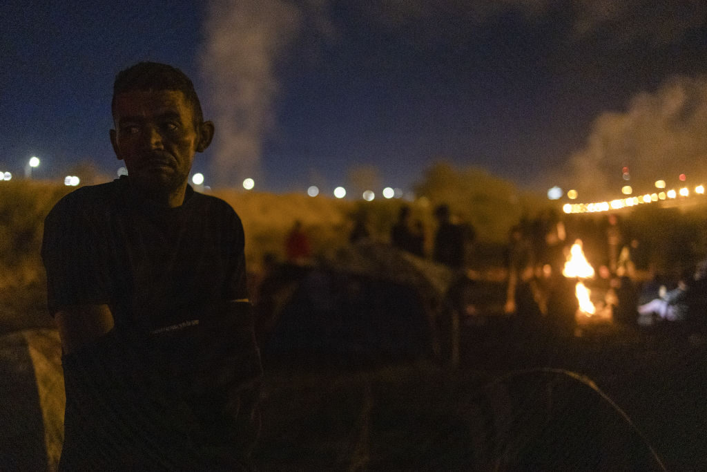 Hundreds of migrants camp Tuesday near the Rio Grande on the border between Mexico and the United States as the Texas National Guard reinforces security with barbed wire and chain-link fencing.